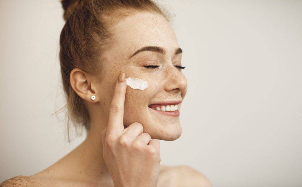woman-smiling-applying-cream-moisturizer